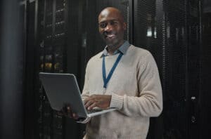 Server, laptop and portrait of black man or technician for data center, system update or cybersecur